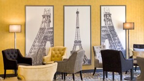 A lobby with three framed Eiffel Tower prints on the wall, a black and a yellow armchair, and a grey armchair. - Gildors Hotel Atmosphère (Düsseldorf)