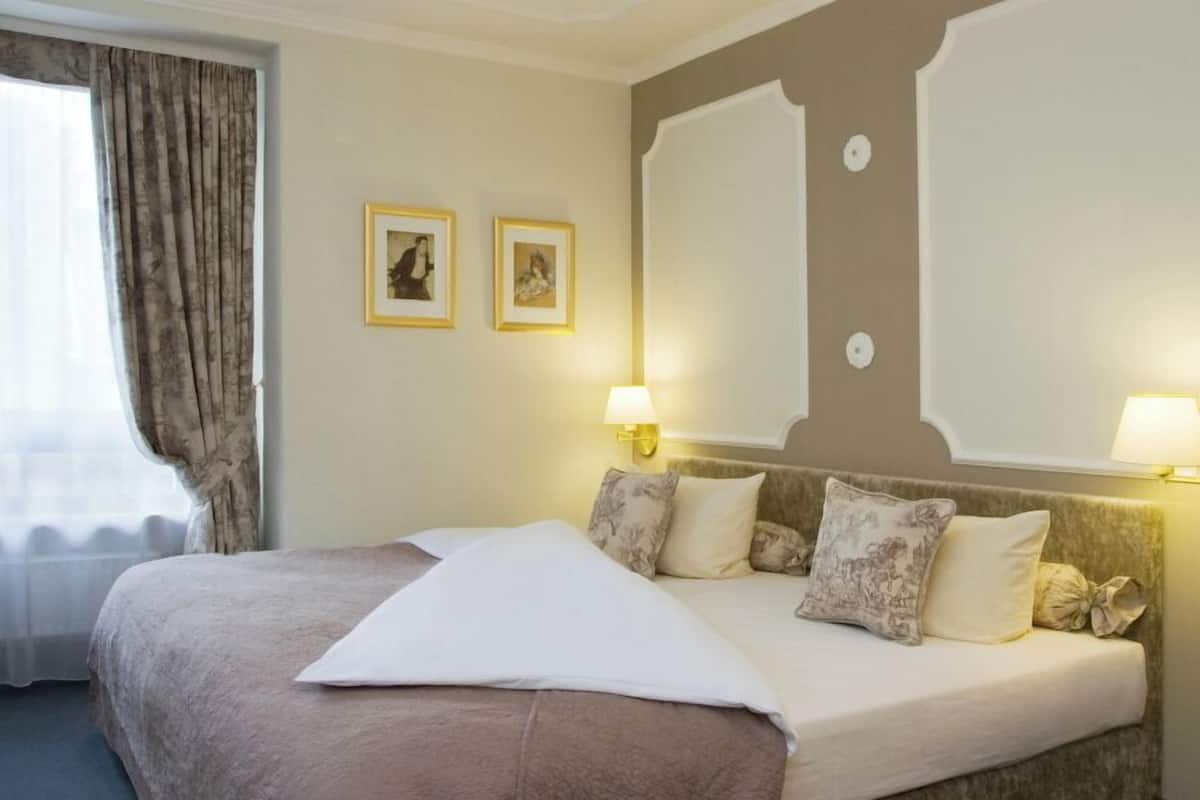 Ein Hotelzimmer mit einem großen Bett, zwei Wandlampen und zwei gerahmten Bildern.
