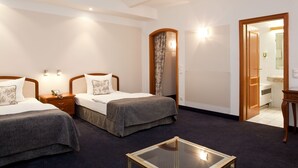 A hotel room with two beds, a small table, and a bathroom visible through an open door. - Gildors Hotel Atmosphère (Düsseldorf)