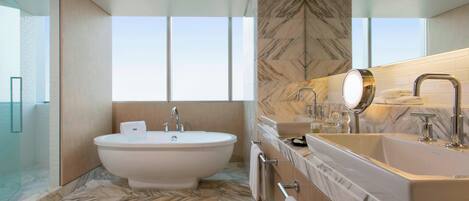 Un baño moderno con una bañera independiente, un tocador con un espejo grande y un lavamanos.