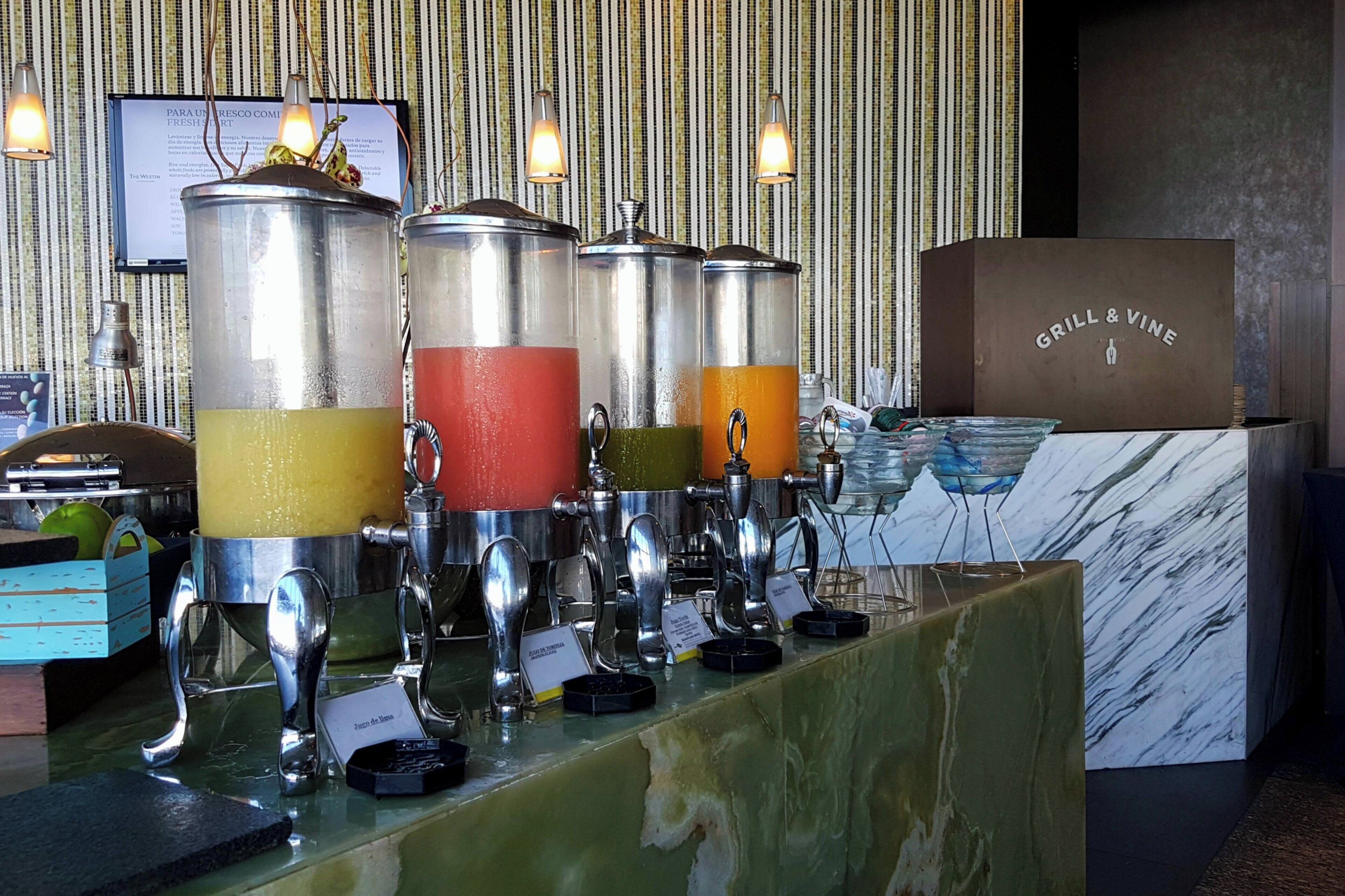 Un bar à jus avec plusieurs distributeurs et une enseigne indiquant « Grill & Vine ».