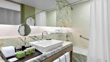 Une salle de bain moderne avec un lavabo en marbre, un miroir à main, un porte-serviettes et un rideau de douche.