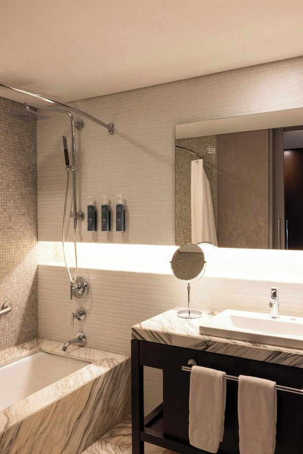 Un baño moderno con bañera, ducha, tocador con espejo y perchero.