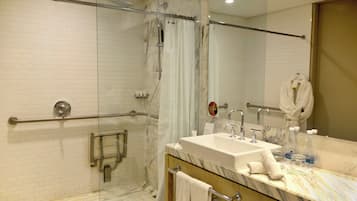 Une salle de bain moderne avec une douche à parois de verre, un lavabo en marbre et un grand miroir.