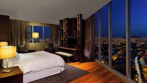 Une chambre d’hôtel moderne dotée d’un grand lit, d’un bureau, d’une télévision et offrant une vue sur la ville.