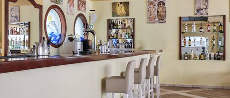 A bar area with a counter, bar stools, and a variety of bottles and glasses.