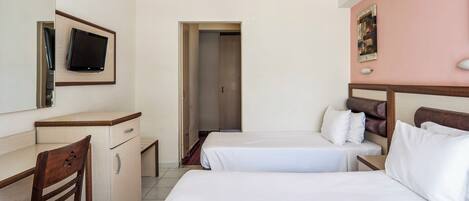 A hotel room with two beds, a desk with a chair, a television mounted on the wall, and a door leading to another room.