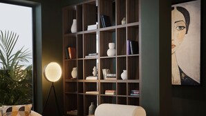 Uma sala de estar moderna com uma estante de madeira, uma mesa de centro redonda e uma poltrona confortável.