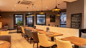 A restaurant interior with wooden tables and chairs, pendant lighting, and a chalkboard menu on the wall. - Hôtel - Restaurant L'évidence (Neufchateau)
