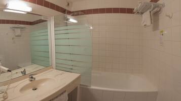 A bathroom with a sink, mirror, glass shower enclosure, and a bathtub.