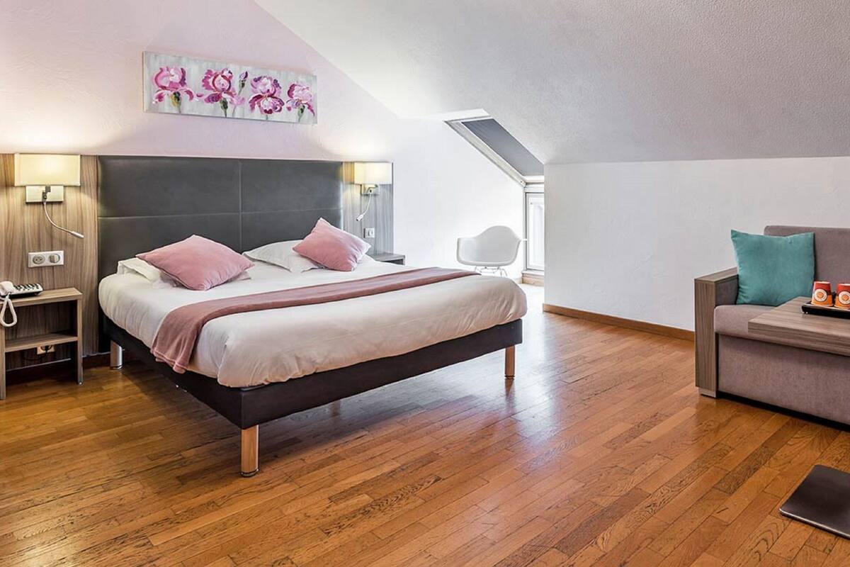 Een moderne slaapkamer met een bed, nachtkastjes, een bureau en een bank.