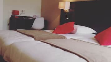 Een hotelkamer met twee bedden, een nachtkastje, een lamp en kunst aan de muren.