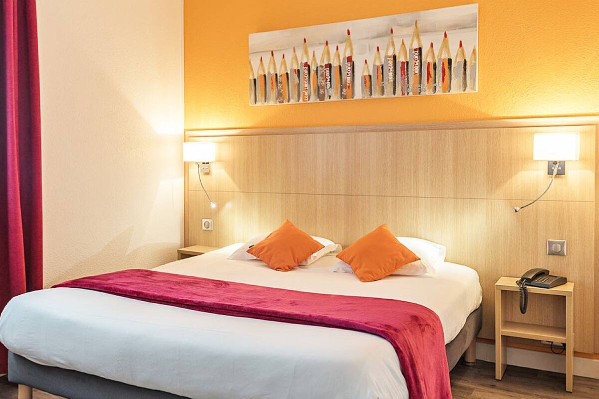 Een hotelkamer met een bed, twee nachtkastjes, een bijzettafeltje met een telefoon en een schilderij aan de muur.