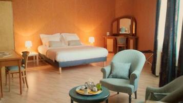 A hotel room with a bed, a desk, a chair, a small table with a tray of items, and a mirror on the wall.