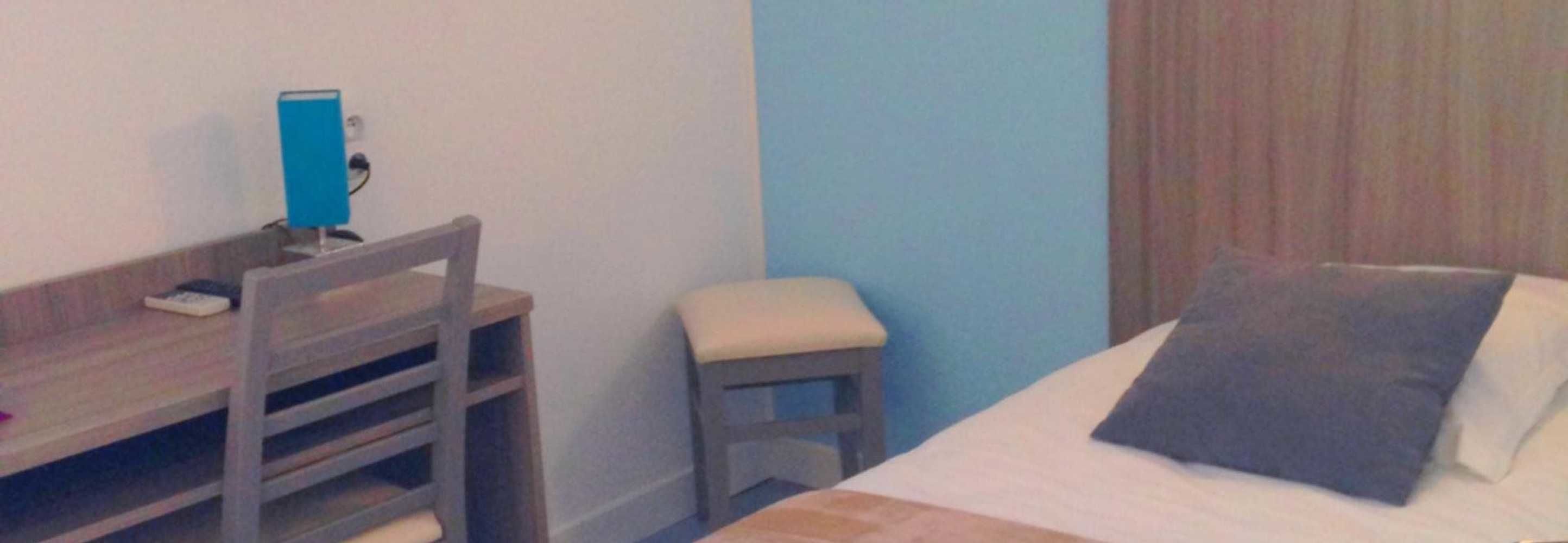 Een slaapkamer met een bed, een bureau en een stoel.