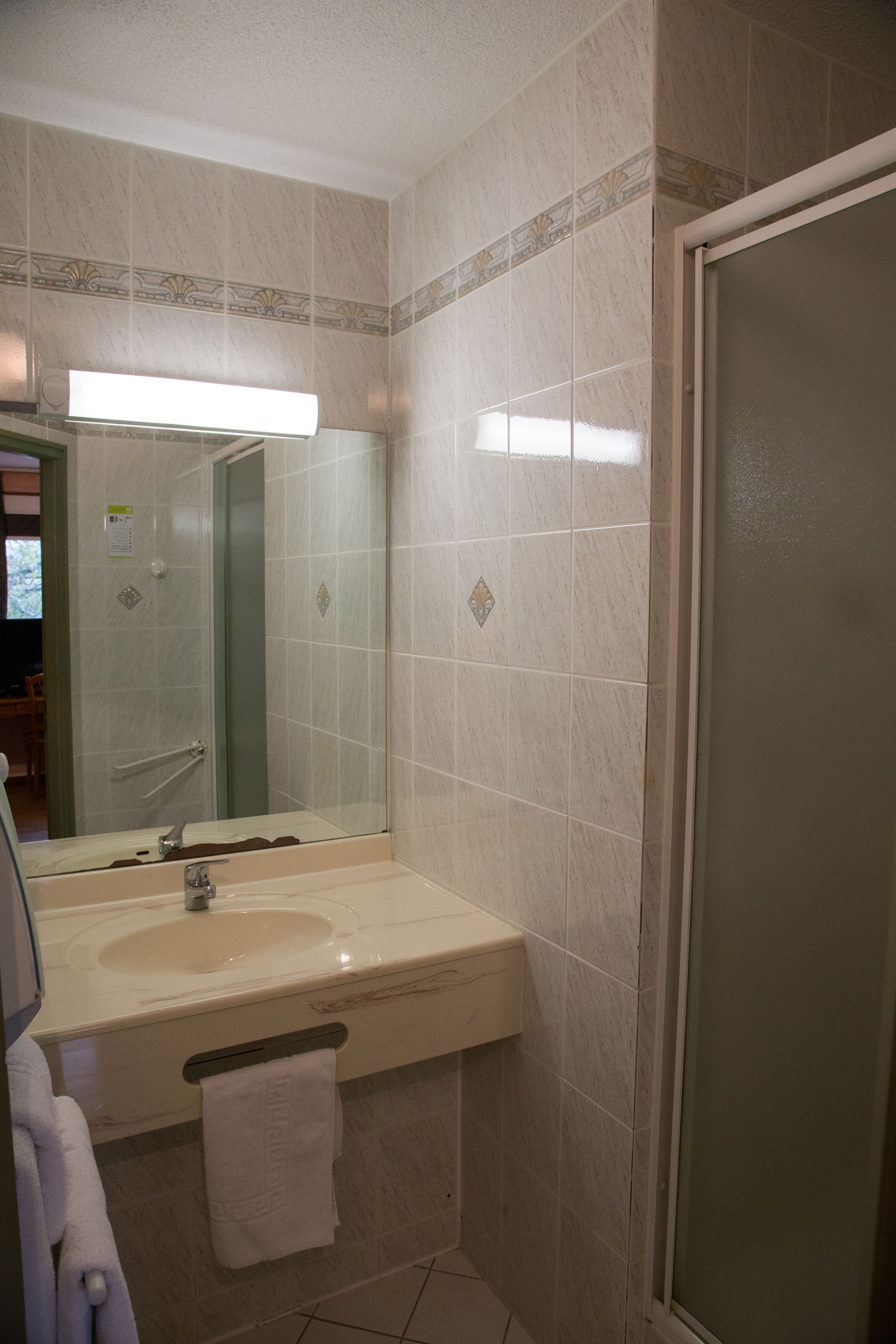 Een badkamer met een wastafel, spiegel en douche.