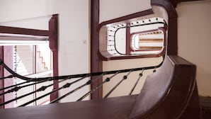 Un escalier en bois avec une rampe métallique et une fenêtre donnant sur l’escalier.