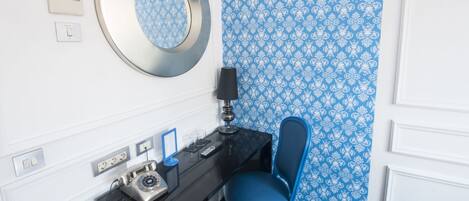 Une chambre d’hôtel équipée d’un bureau, d’une chaise, d’un téléphone et d’un miroir fixé au mur.