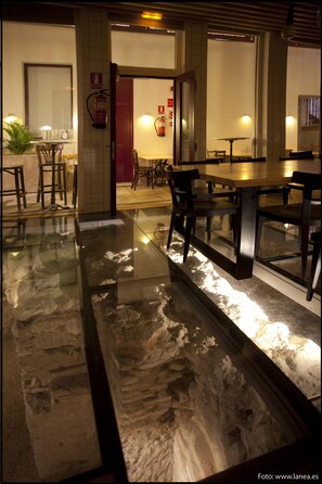 A restaurant with a glass floor, tables, chairs, and a fire extinguisher on the wall. - Posada del Dragón Boutique Hotel (Madrid)
