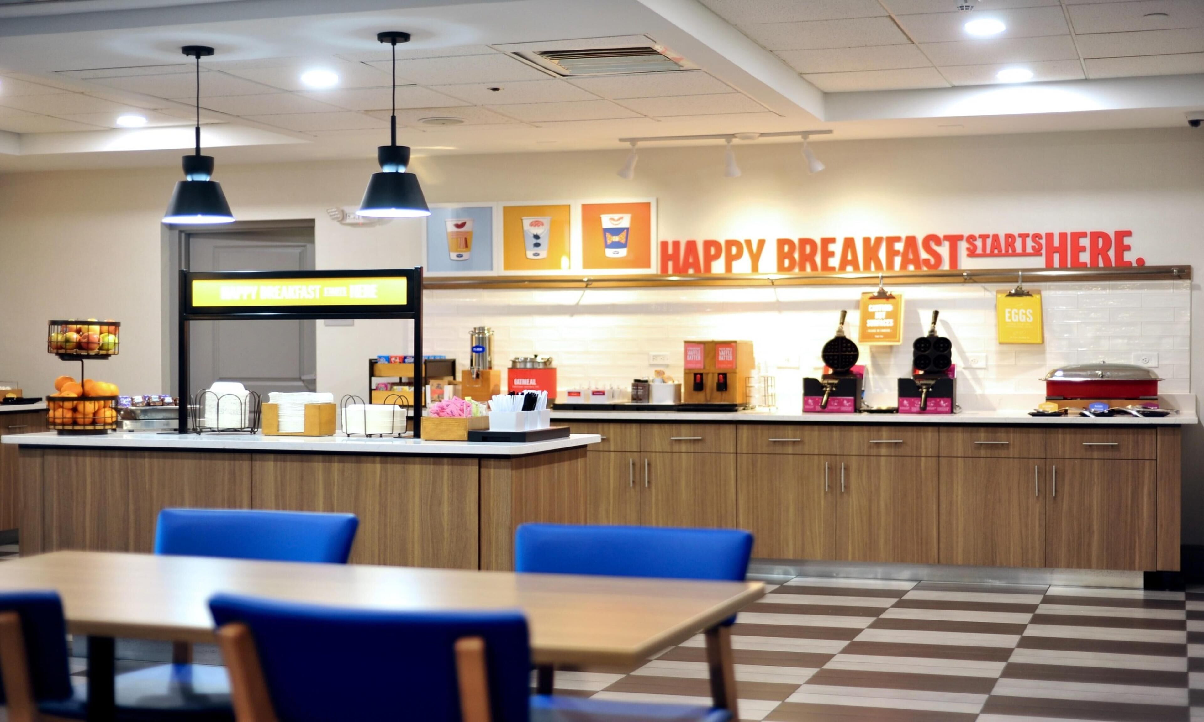 Een ontbijtruimte met een aanrecht, zitplaatsen en een bord waarop staat 'HAPPY BREAKFAST START HERE'.
