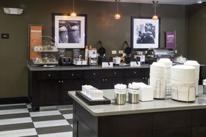 A breakfast bar with waffle makers, coffee machines, and a variety of breakfast items.