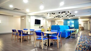 Eine moderne Hotelhalle mit Holzboden, blau-gelben Sitzgelegenheiten und einem großen blauen Sofa.