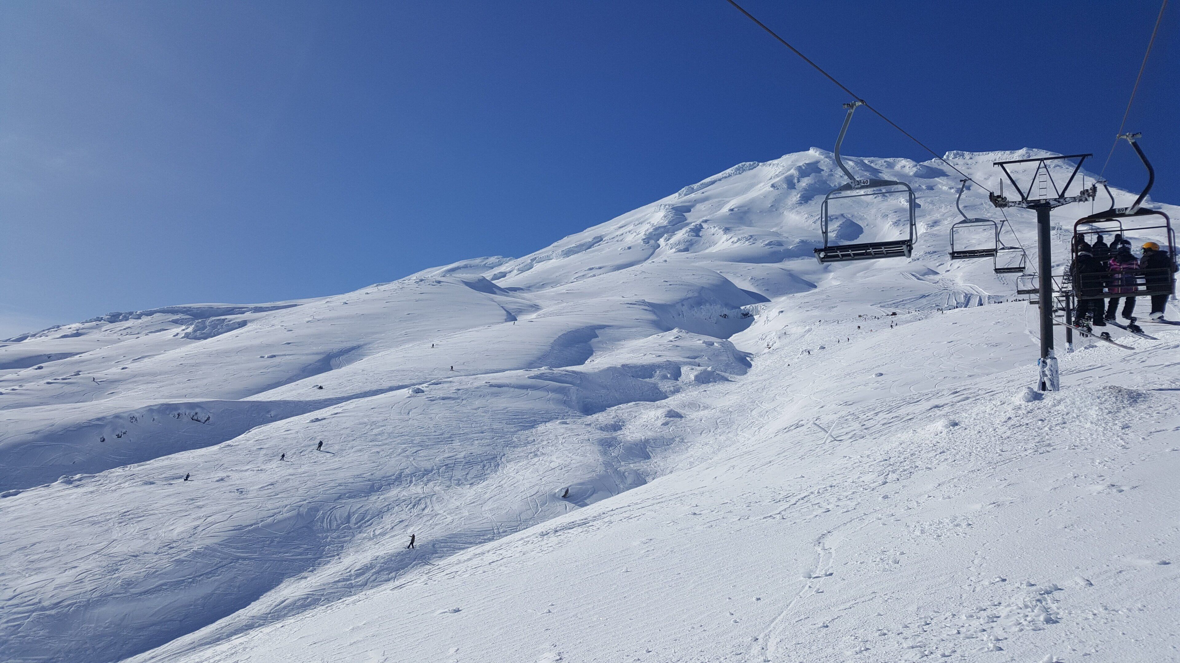 A snowy mountain slope with a ski lift and a chairlift.