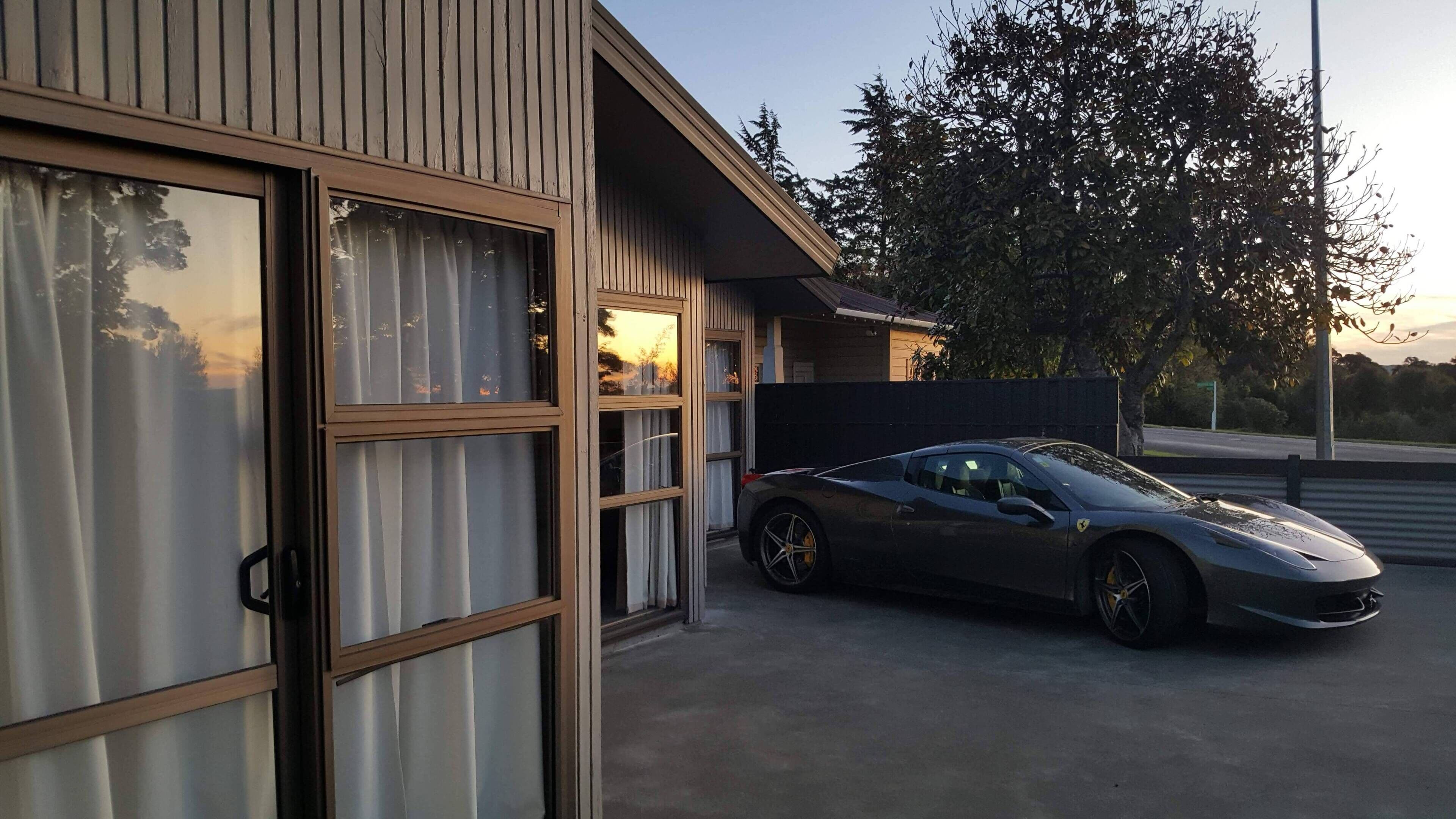 A modern building with large windows and a parked sports car.