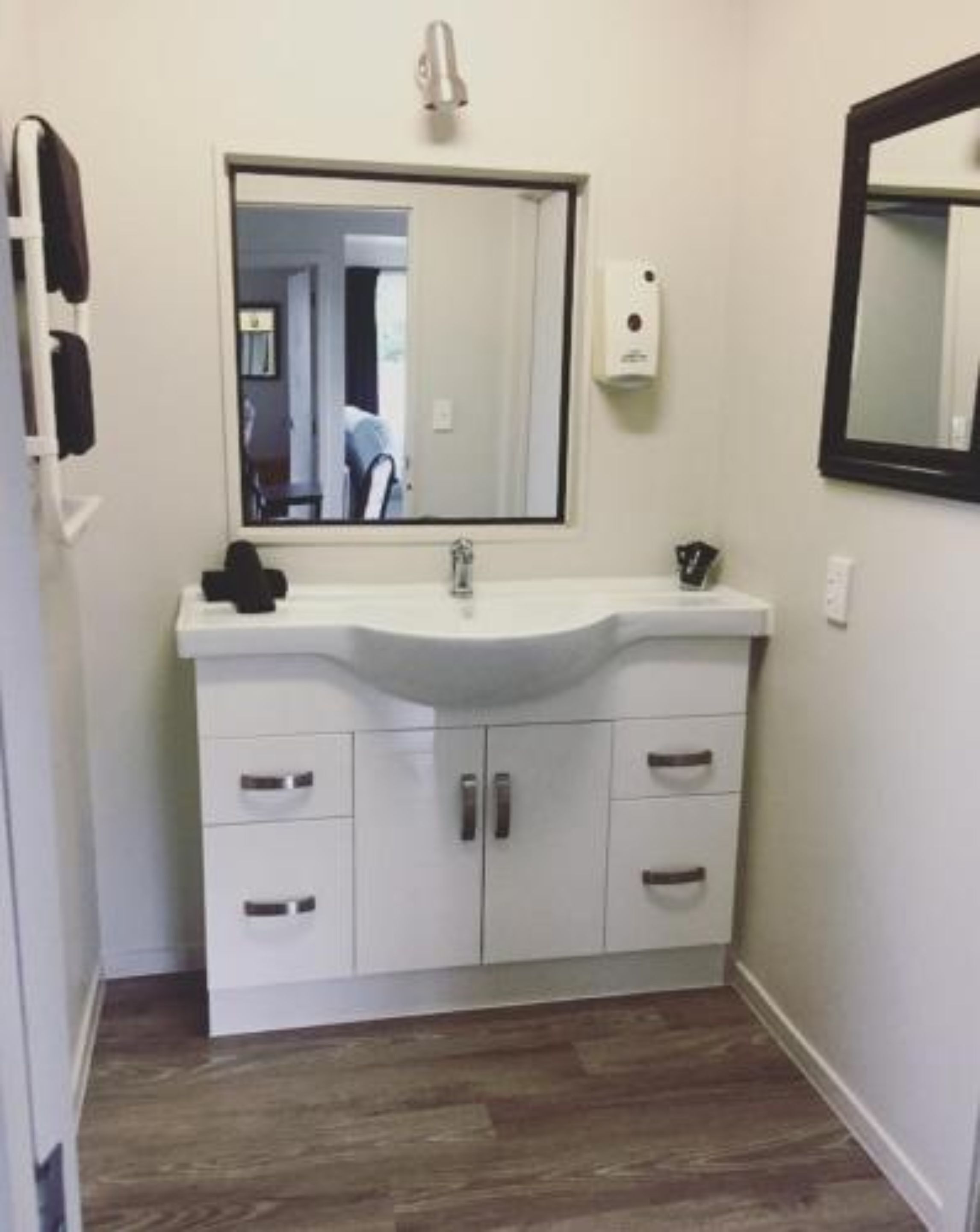 A bathroom with a white vanity, a mirror, and a sink.