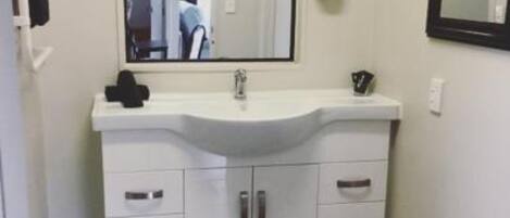 A bathroom with a white vanity, a mirror, and a sink.