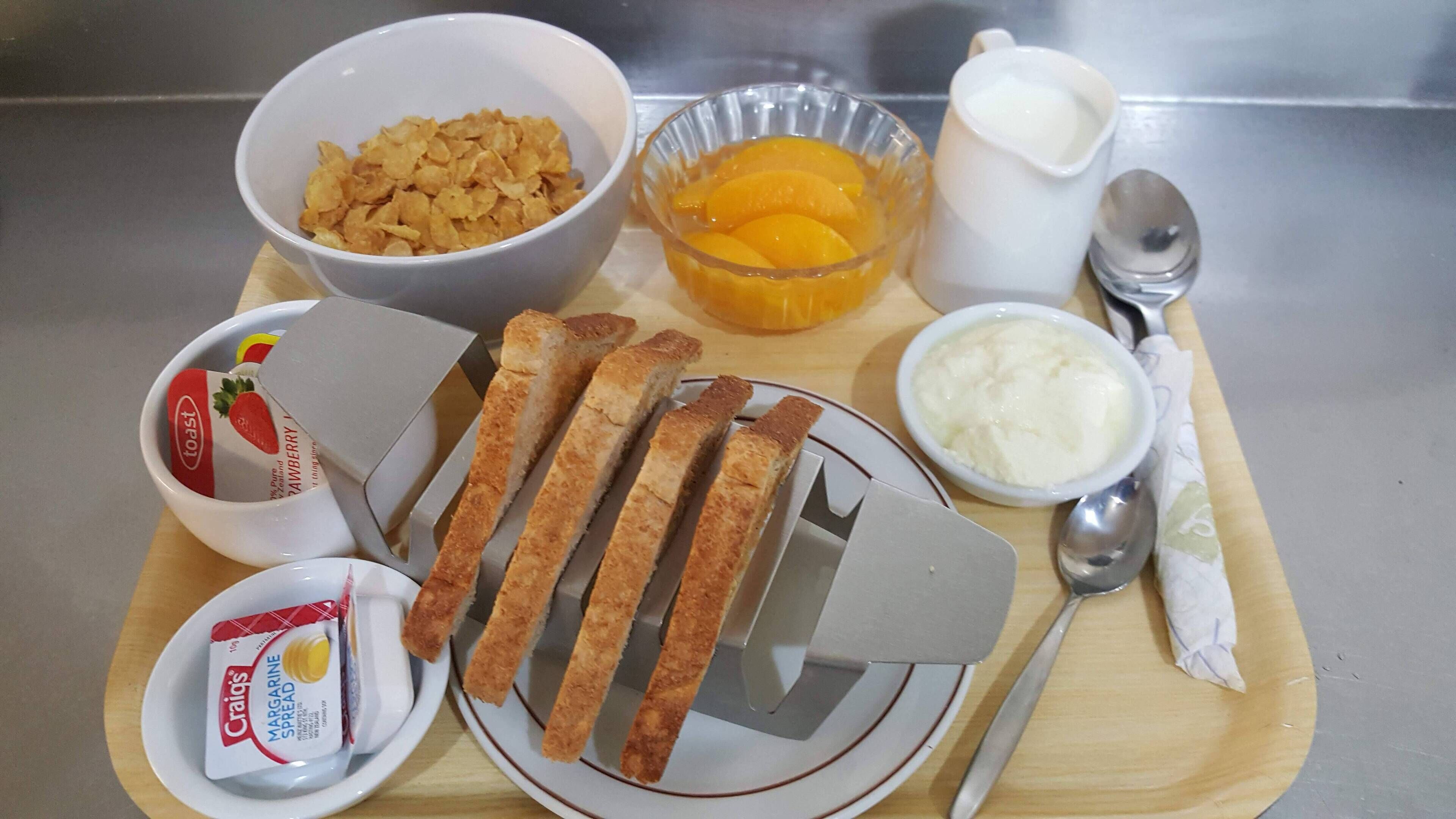Ein Frühstückswagen mit Toast, Müsli, Orangenscheiben, Margarine und Joghurt.