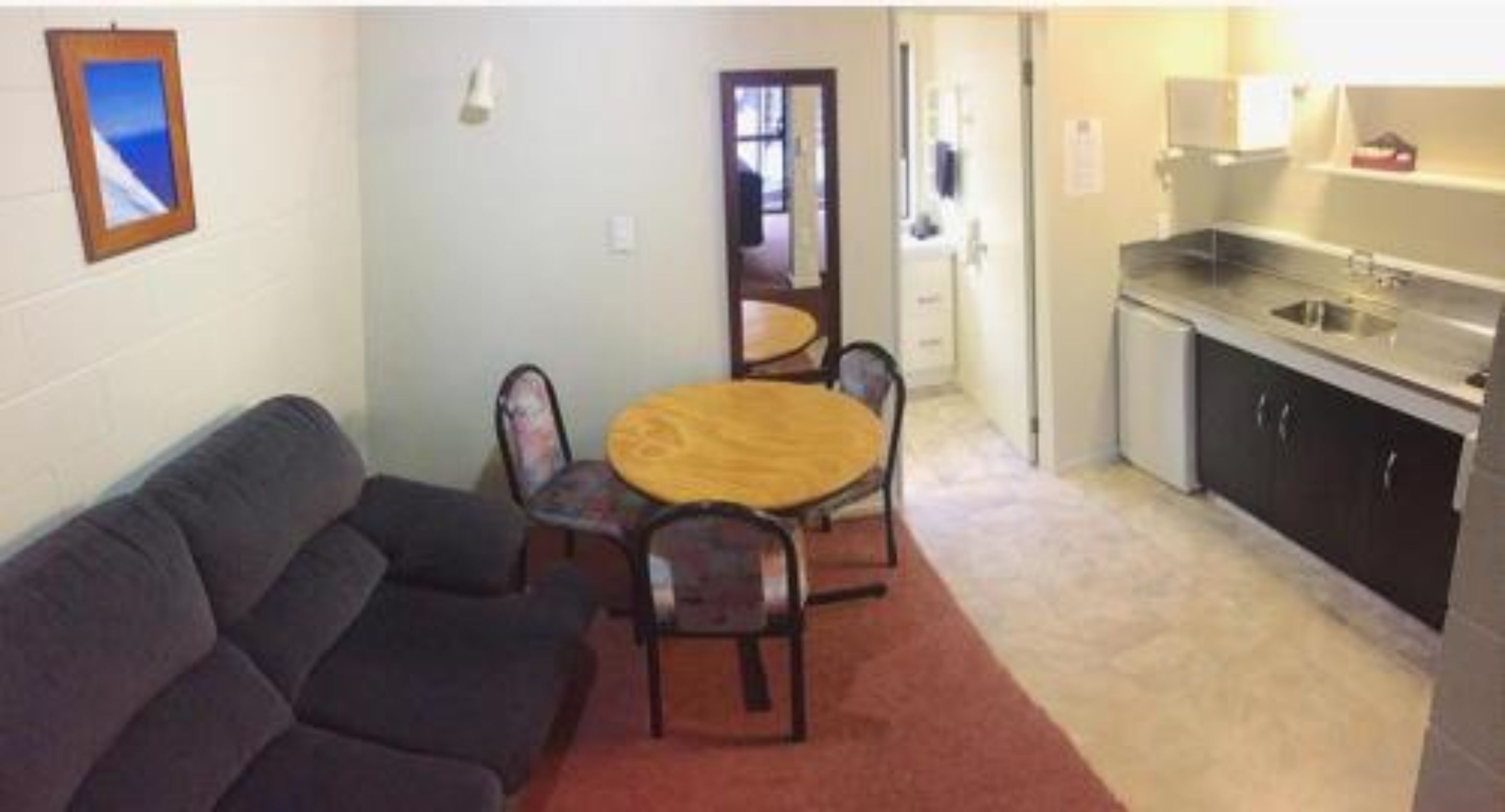 A compact living space with a sofa, a round dining table, and a kitchenette.