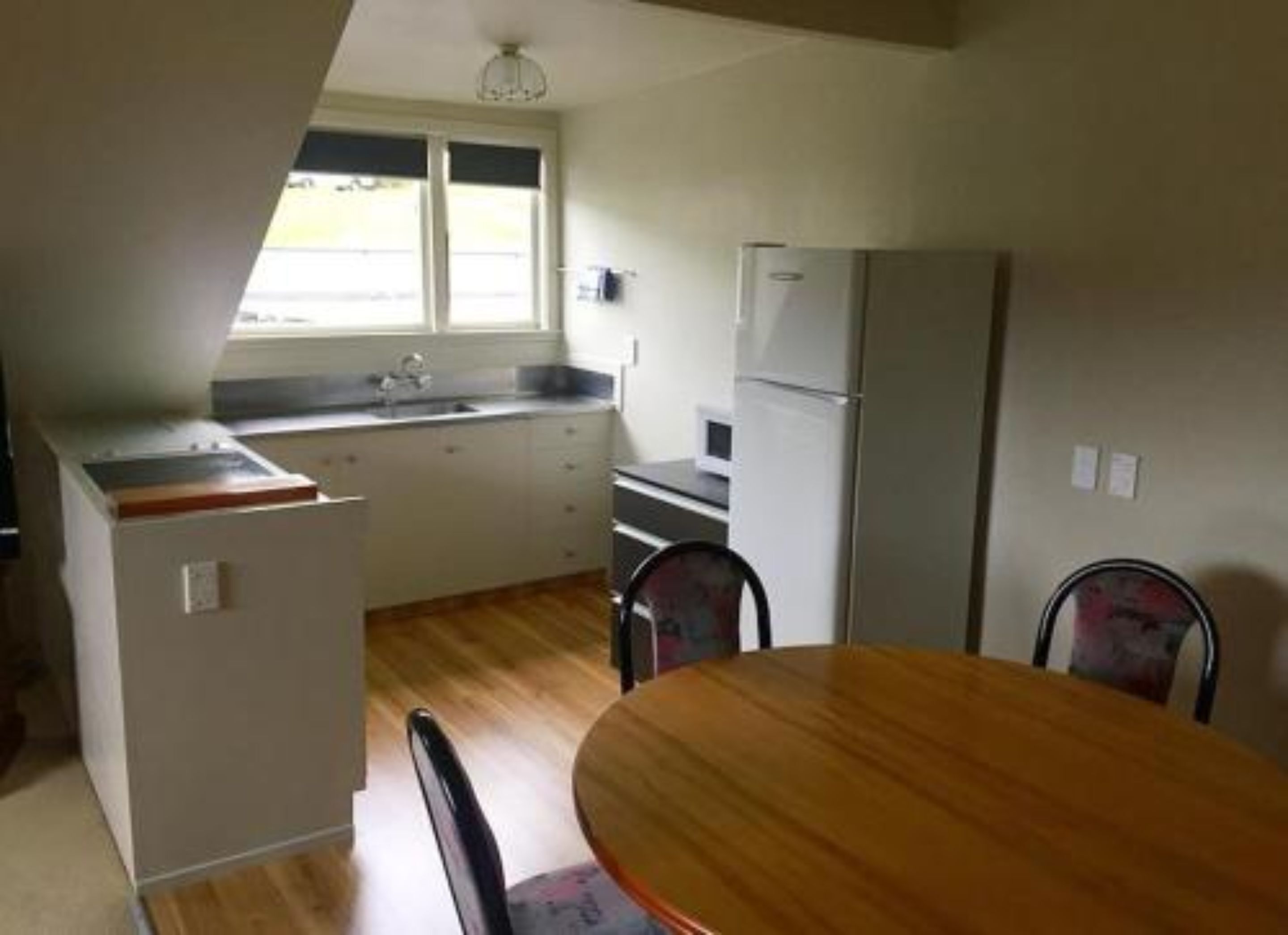 A compact kitchen with a sink, refrigerator, and a dining area with a table and chairs.
