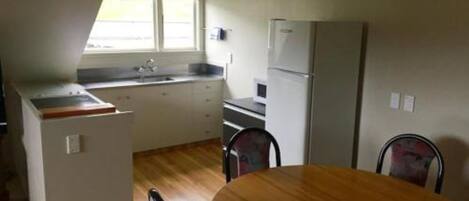A compact kitchen with a sink, refrigerator, and a dining area with a table and chairs.