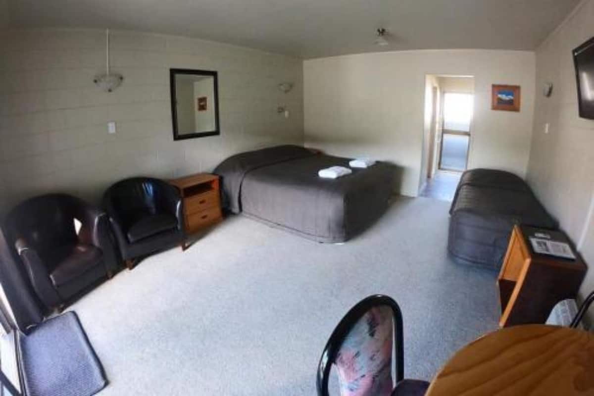 A compact room with a bed, a desk, a chair, and a small table.