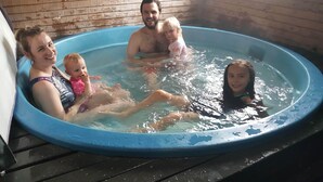 Eine Familie in einem kleinen, runden, blauen Pool mit Holzverkleidung.