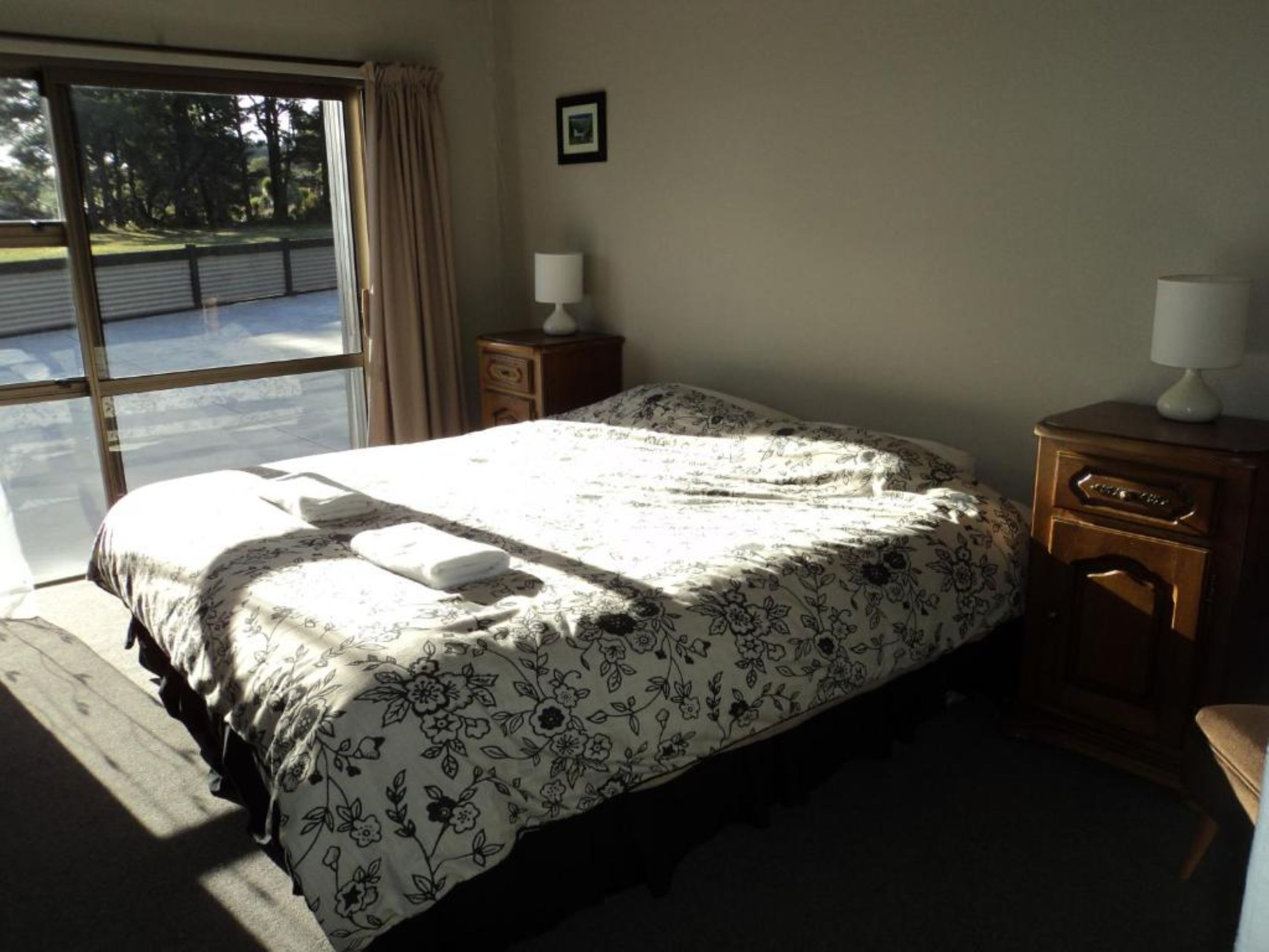 Een slaapkamer met een groot bed, een nachtkastje, een kast en een raam met gordijnen.