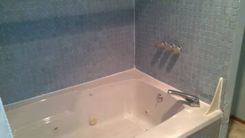 A bathroom with a white bathtub, blue tiled walls, and a white sink.