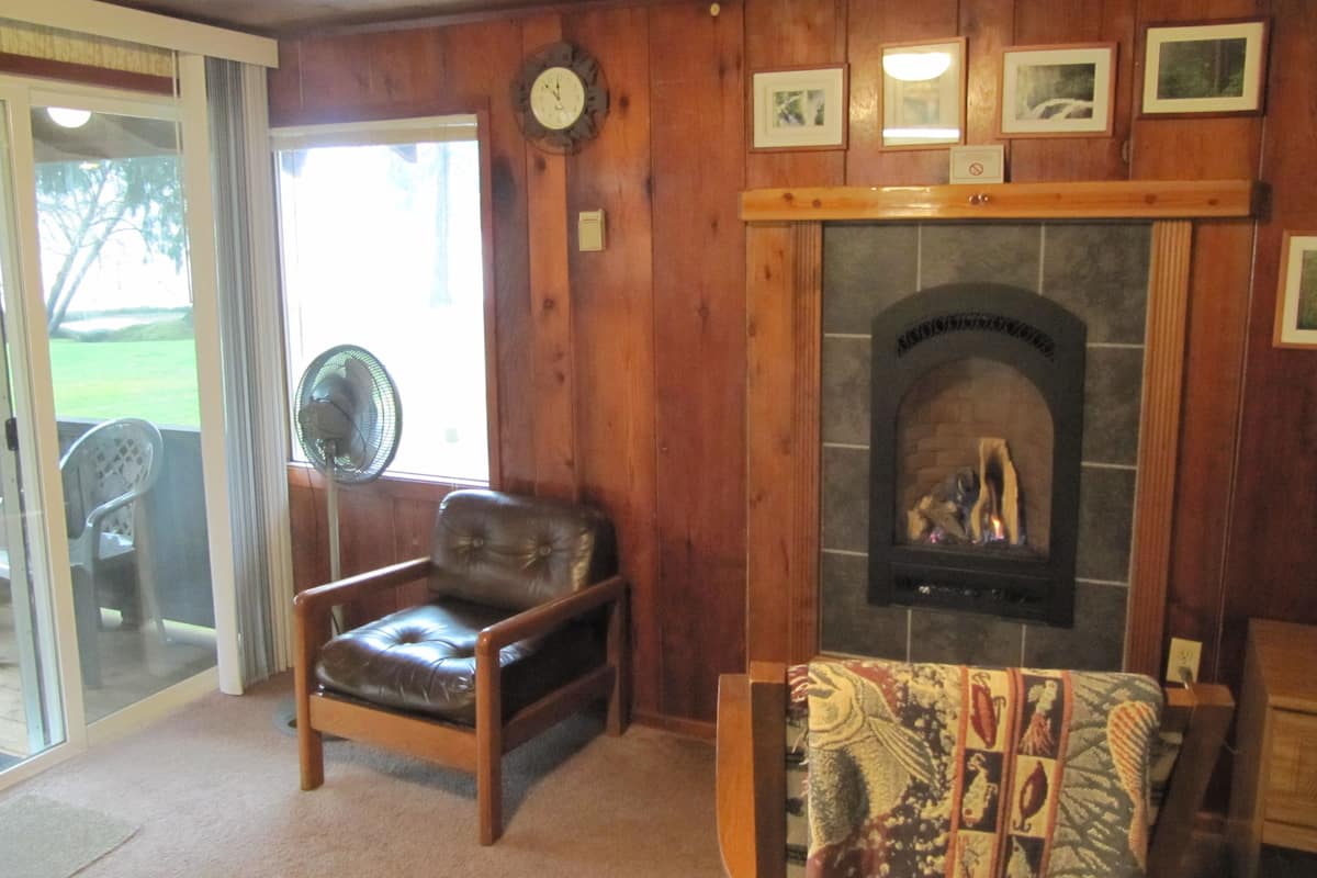 Un salón acogedor con chimenea, un sillón de cuero y un ventilador.