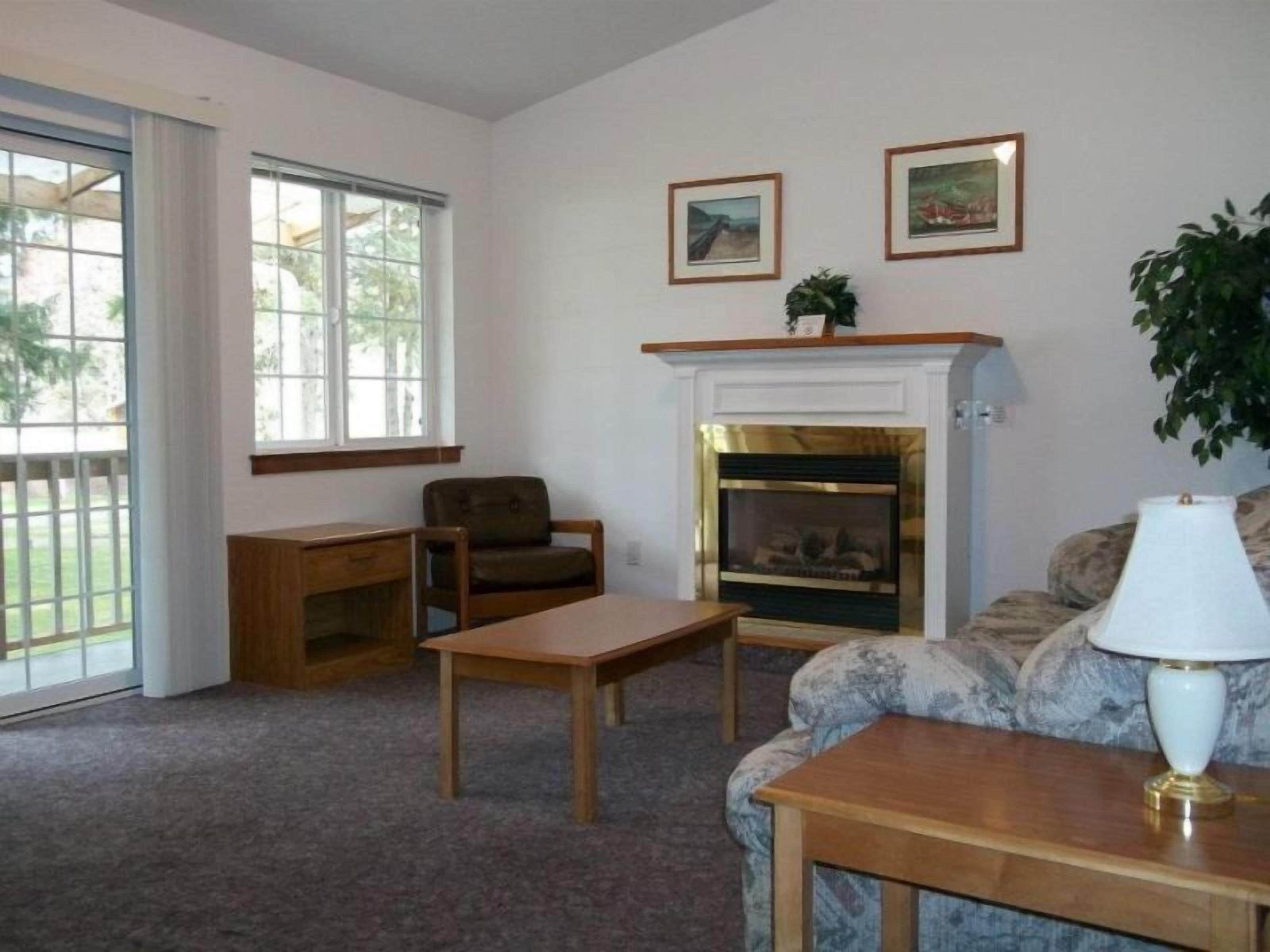 A living room with a fireplace, a sofa, a chair, a table, and two framed pictures on the wall.