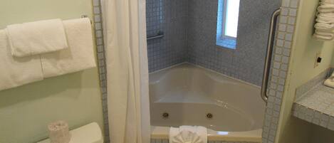 Un baño con bañera, inodoro, cortina de ducha y ventana.