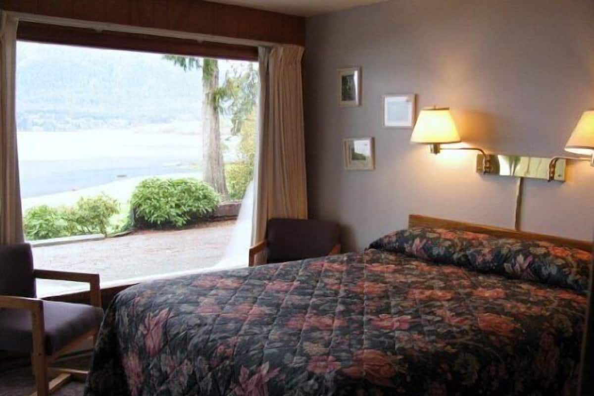 Habitación de hotel con cama, una silla, un escritorio y vistas al exterior.