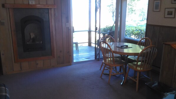 A cozy room with a fireplace, wooden dining table, and chairs.