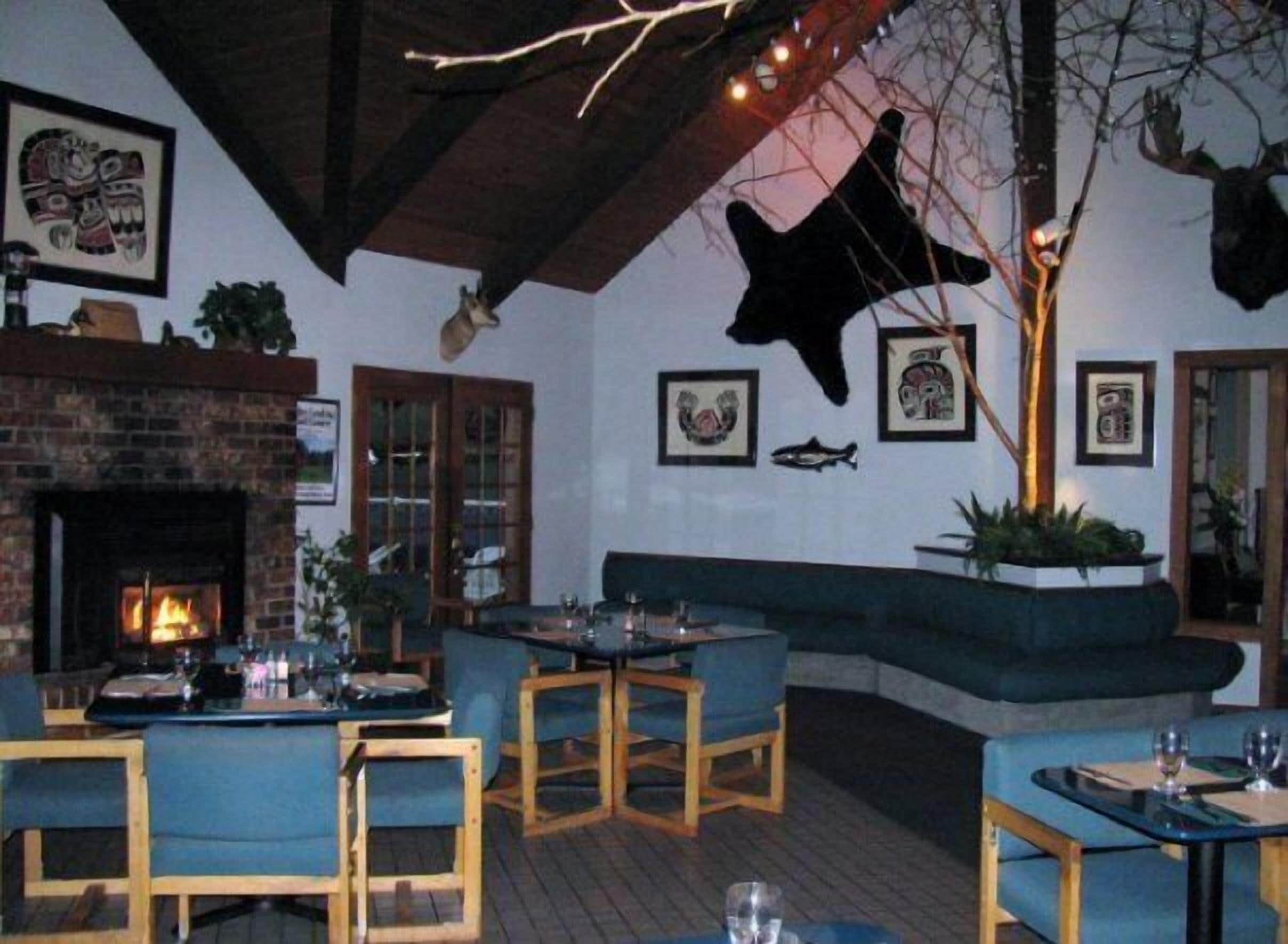 Un restaurante con chimenea de ladrillo, mesas y sillas de madera, y monturas de animales en las paredes.