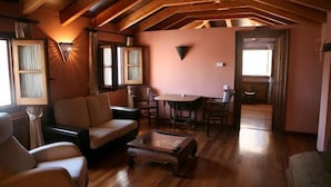 A cozy living room with a wooden ceiling, a sofa, a coffee table, and a dining area with chairs and a table. - La Colegiata de Ronda (Ronda)