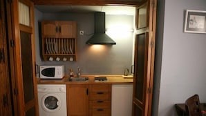 A compact kitchen with wooden cabinets, a microwave, a washing machine, and a sink. - La Colegiata de Ronda (Ronda)