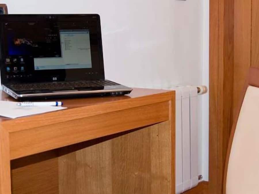 Um computador portátil sobre uma secretária de madeira, com um bloco de notas ao lado.