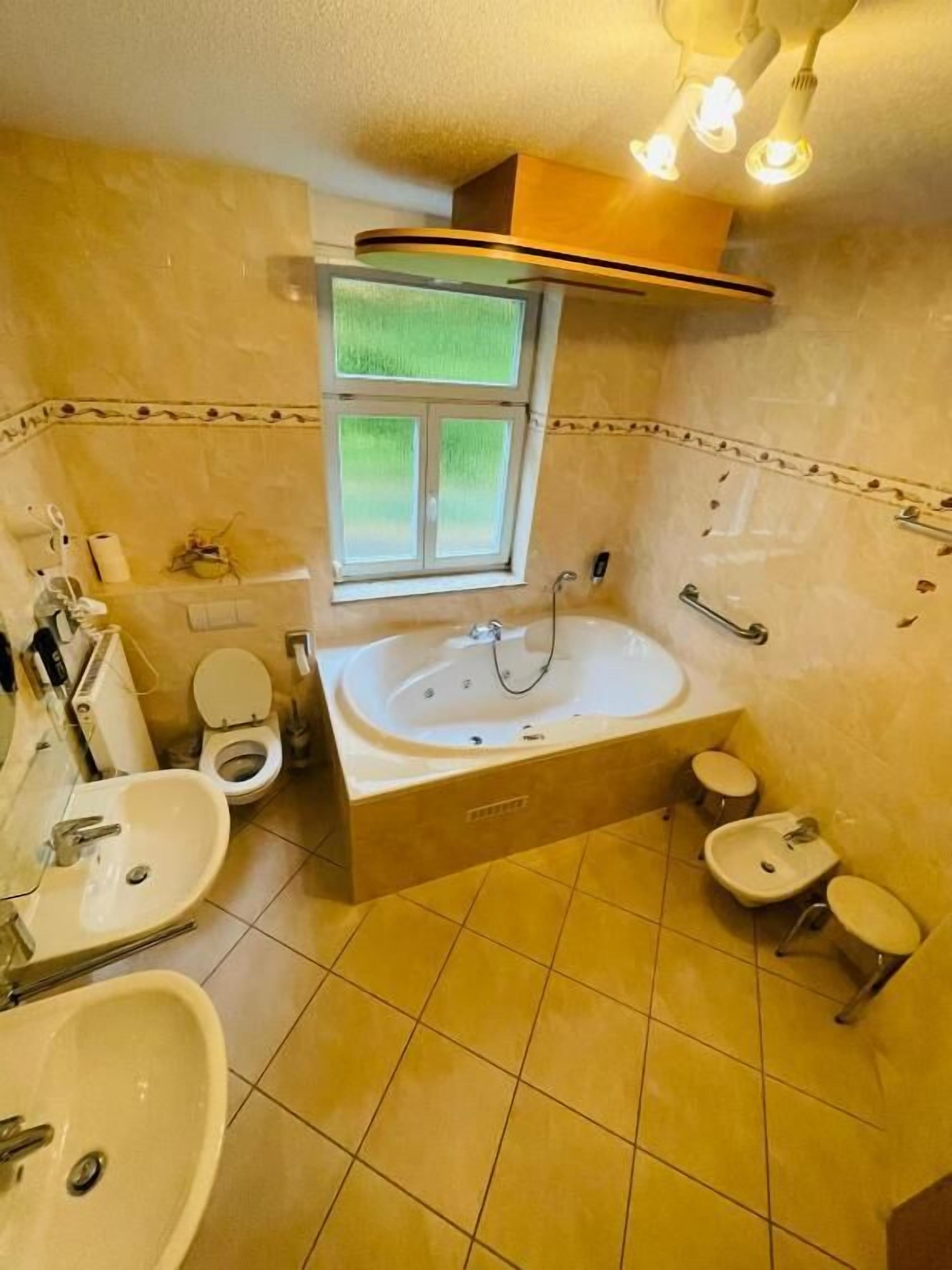 Un baño con bañera, dos lavamanos, inodoro y ventana.