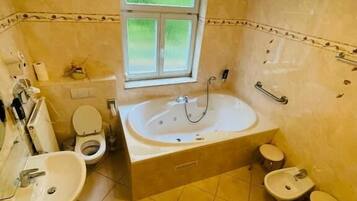 Une salle de bain avec une baignoire, deux lavabos, des toilettes et une fenêtre.
