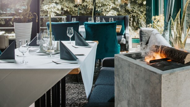 Un comedor con una mesa dispuesta para dos personas, sillas y una chimenea empotrada.